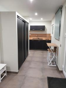 una cocina con armarios negros, fregadero y encimera en Studio meublé - Comme à la maison en Belfort