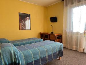 a bedroom with two beds and a tv and a window at Hotel Giardino in Pieve di Cadore