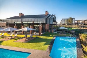 a large building with a pool and umbrellas at Charms and bows studio apartment -near ORT airport in Boksburg
