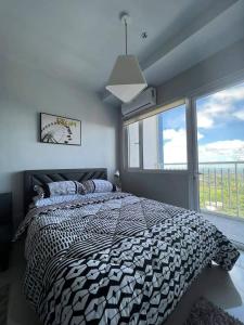 a bedroom with a bed and a large window at SMDC Wind residences in Tagaytay