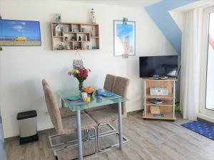 a dining room with a table and chairs and a television at Ferienwohnung Ausblick in Norddeich