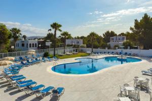 uma grande piscina com espreguiçadeiras azuis e um resort em Hotel Apartamentos Vibra Monterrey em San Antonio Bay