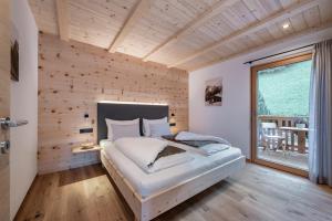 sypialnia z łóżkiem z drewnianą ścianą w obiekcie Gschlunerhof w mieście Castelrotto