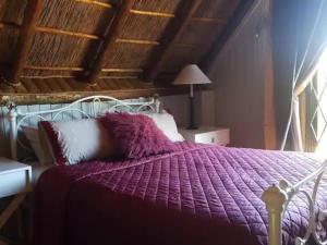 un letto con piumone viola in una camera da letto di SHABBY FUFU LIFESTYLE FARM a Plettenberg Bay