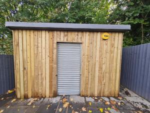 a wooden shed with a door in a fence at Beautiful 4 bedroom house near town centre. With Bike Store Perfect for Bike Park Wales in Merthyr Tydfil