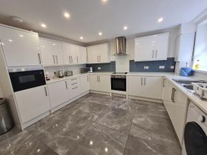 a kitchen with white cabinets and a tile floor at Beautiful 4 bedroom house near town centre. With Bike Store Perfect for Bike Park Wales in Merthyr Tydfil