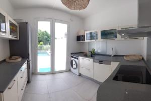 a white kitchen with a sink and a washing machine at Villa en bord de mer, vue mer au Diamant in Le Diamant