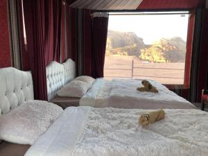 two beds in a room with a large window at Blue Camel in Wadi Rum