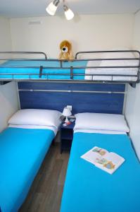 two twin beds in a room with a blue bed at Happy Camp mobile homes in Villaggio Camping Baia Domizia in Baia Domizia