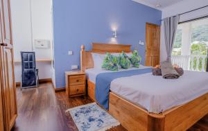 a bedroom with two beds with blue walls and a window at The Cove Holiday Apartment in Bel Ombre