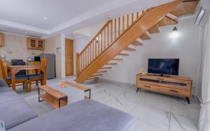 a living room with a couch and a tv and a staircase at The Cove Holiday Apartment in Bel Ombre