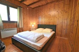 a bedroom with a bed in a wooden wall at Hortensias in Somme-Leuze