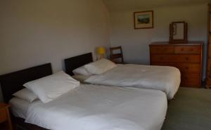 um quarto com 2 camas e uma cómoda com um espelho em Craignuisq Farmhouse em Pitlochry