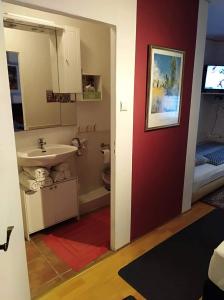 ein Bad mit einem Waschbecken, einem WC und einer roten Wand in der Unterkunft Hotel/Restaurant Adria in Windhagen