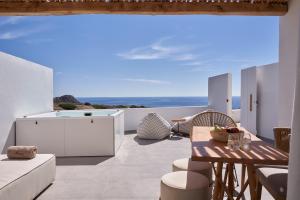 Armony Suites Milos في Paliochori: غرفة معيشة مع طاولة وإطلالة على المحيط
