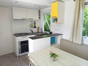MazoにあるCasitas Mobil Homeの白いキャビネットと花のテーブル付きのキッチンが備わります。