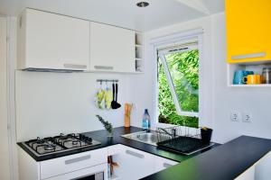 a kitchen with white cabinets and a black counter top at Casitas Mobil Home in Mazo