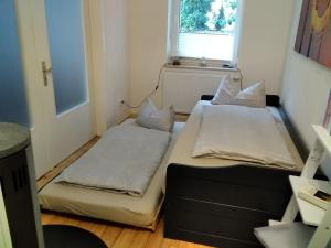 2 Betten in einem kleinen Zimmer mit Fenster in der Unterkunft Gästhaus Am Hilkenberg in Lichtenau