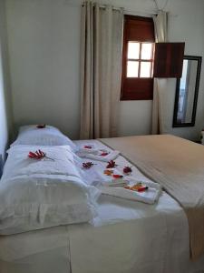 Una cama blanca con sábanas blancas y flores rojas. en Casa da Marluce, en Fernando de Noronha