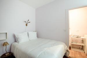 a white bed in a white bedroom with a window at Le Monarque - Appartement avec jardin in Chaville