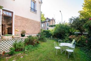 a patio with a table and chairs in a yard at Le Monarque - Appartement avec jardin in Chaville