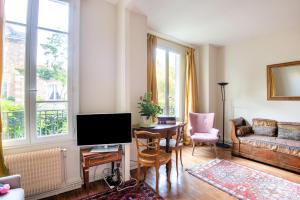 a living room with a couch and a table with a television at Le Monarque - Appartement avec jardin in Chaville