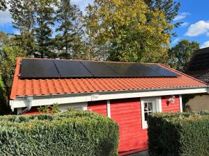 una casa roja con paneles solares en el techo en Blockbohlenhaus Plau am See, en Plau am See