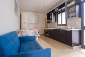 a living room with a blue couch and a kitchen at Casa Matilde in Porto Cesareo
