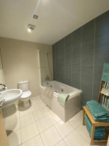 a bathroom with a tub and a toilet and a sink at Cosy 3 bedroom apartment in central Portrush with sea views in Portrush