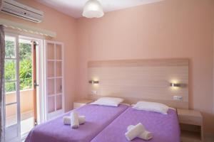 um quarto com uma cama roxa e 2 almofadas brancas em Dora Apartment Pagoi 2 em Agios Georgios Pagon