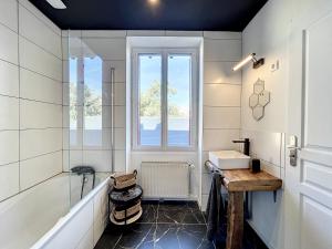 baño con bañera, lavabo y ventana en Appart LA MANUFACTURE - Maison 1911 - confort & prestige en Gien