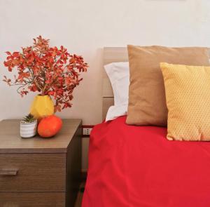 a bed with a red blanket and a vase with a plant on a table at TraMonti Apartments in Poggio Picenze
