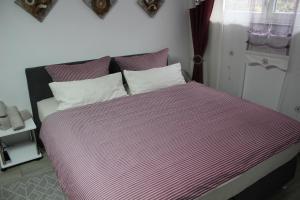 ein Bett mit rosa und weiß gestreiften Laken und Kissen in der Unterkunft Studio-Appartement Neunburg vorm Wald in Neunburg vorm Wald