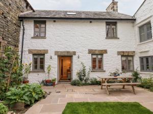 a white house with a picnic table in the yard at Monkey Puzzle Cottage in Sedbergh