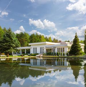納達金的住宿－Perła Leśna Nadarzyn，一座白色的建筑,前面有一个池塘