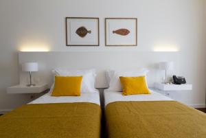 una camera con 2 letti con cuscini gialli di Hotel Vila D'Óbidos a Óbidos