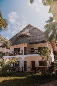 a large white building with a thatched roof at Blue Oyster Hotel in Jambiani