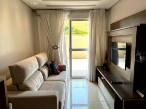 een woonkamer met een witte bank en een televisie bij Apartamento Villa Nova Master Collection in Passo Fundo