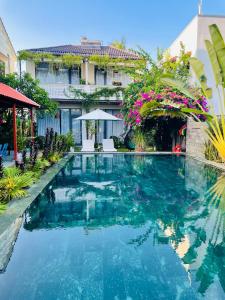 a swimming pool in front of a building with flowers at Hoi An Cabbage Garden in Hoi An