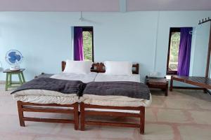 a large bed in a bedroom with purple curtains at BAANZ CABIN - managed by The Silver Oak Place in Pithorāgarh