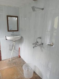 baño con lavabo, espejo y cubo en BAANZ CABIN - managed by The Silver Oak Place, en Pithorāgarh