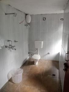 a bathroom with a toilet and a bucket in it at BAANZ CABIN - managed by The Silver Oak Place in Pithorāgarh