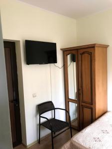 a bedroom with a chair and a television on the wall at Casa Rosa in Băile Olăneşti