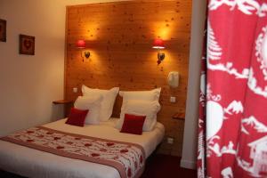 a hotel room with a bed with red and white pillows at Hôtel Les Charmilles in Besse-et-Saint-Anastaise