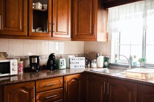 a kitchen with wooden cabinets and a counter top at Apartamento Bela Vista Ilha Terceira in Feteira