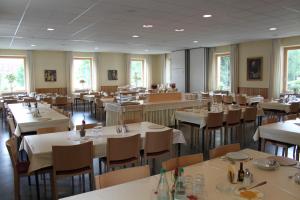 a dining room with white tables and chairs and windows at St. Bonifatiuskloster - Geistliches Zentrum in Hünfeld