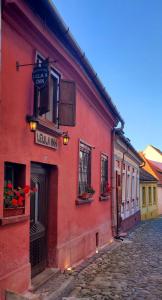 a red building with a sign on a street at Pensiunea Lelila Inn in Sighişoara