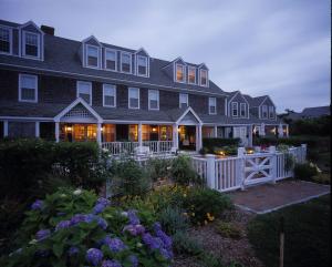 une grande maison avec une clôture blanche devant elle dans l'établissement The Wauwinet Nantucket, à Wauwinet