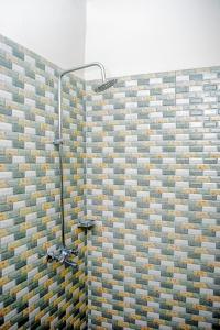 een douche in een badkamer met een tegelwand bij Zanzibar Spice Nest Apartment in Stone Town