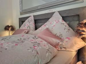 a bed with pink and pink pillows on it at Gasthaus Paula in Üdersdorf